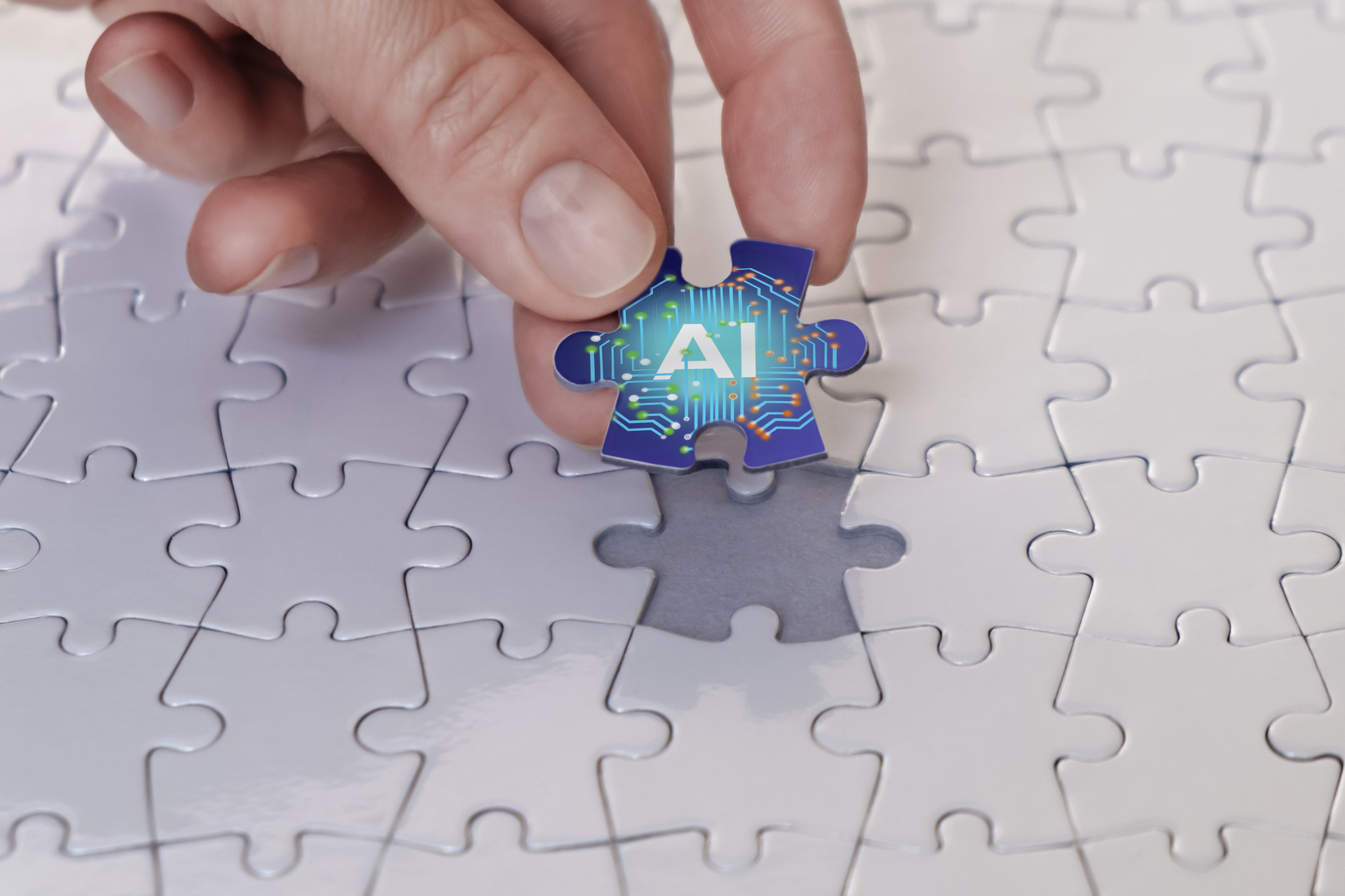 Hand placing an AI puzzle piece into a business solution